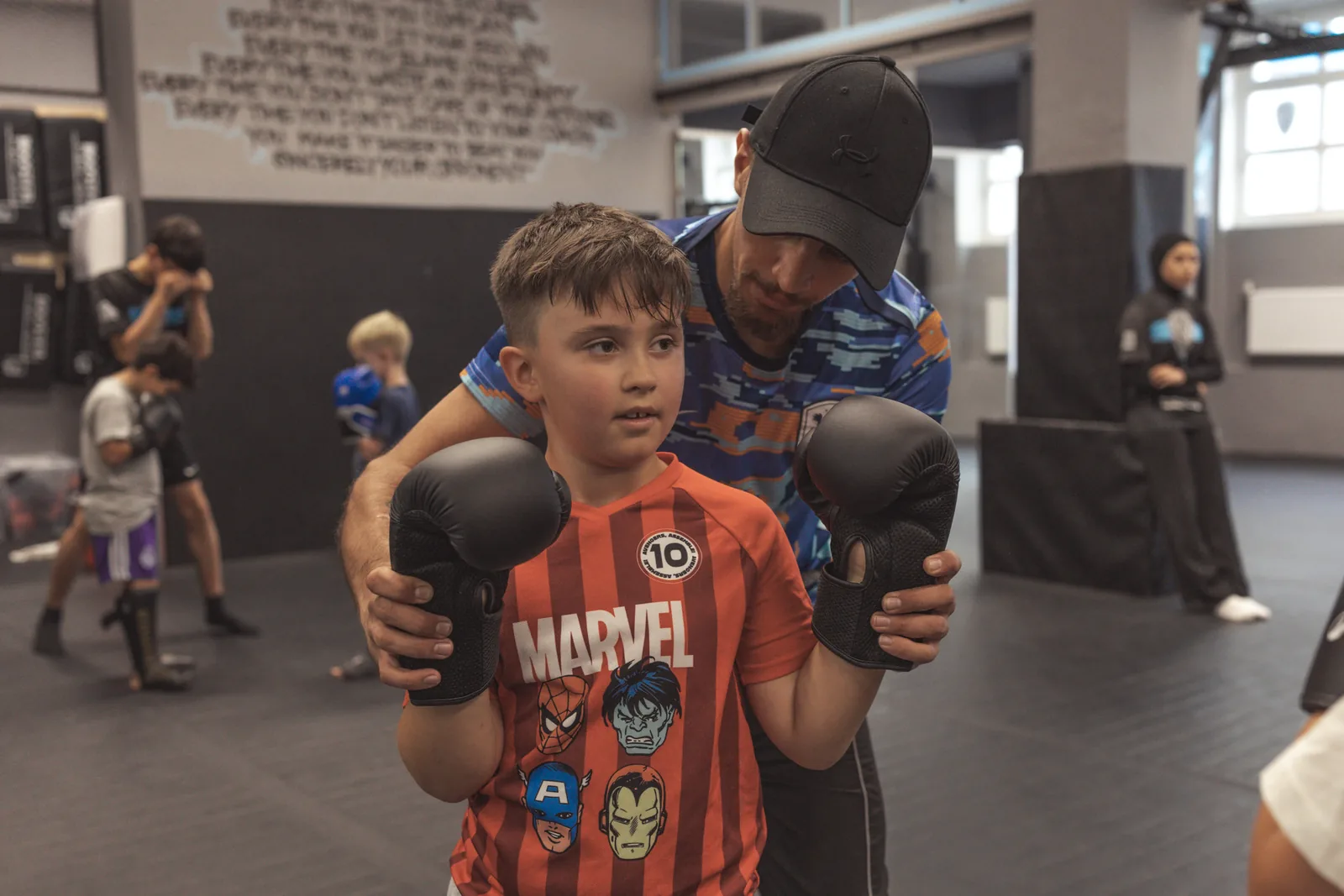 Trainer korrigiert einem Jungen geduldig die Deckung im Kindertraining