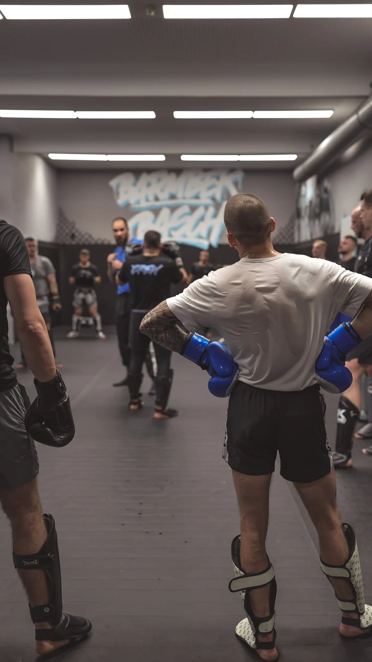 Kickboxer mit Boxhandschuhen und Schienbeinschonern im Wettkampftraining