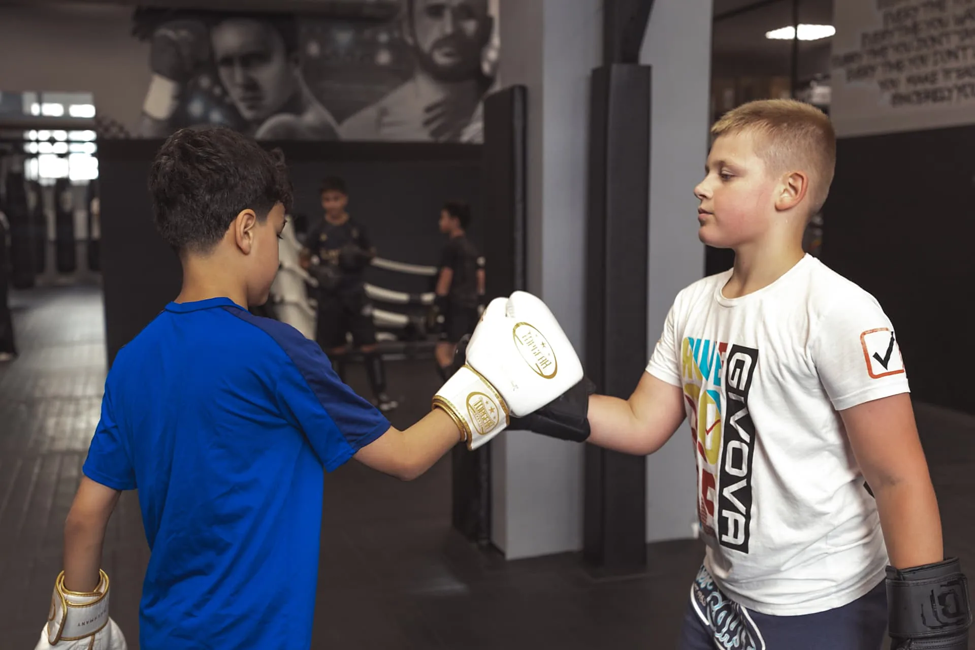 Zwei Jungen tippen im Kindertraining die Boxhandschuhe zusammen, bevor die Partnerübung startet