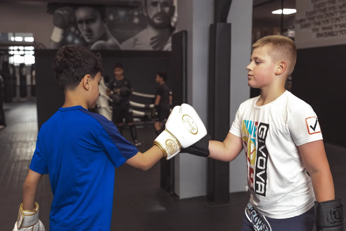 Zwei Jungs klatschen im Kindertraining mit den Boxhandschuhen ab