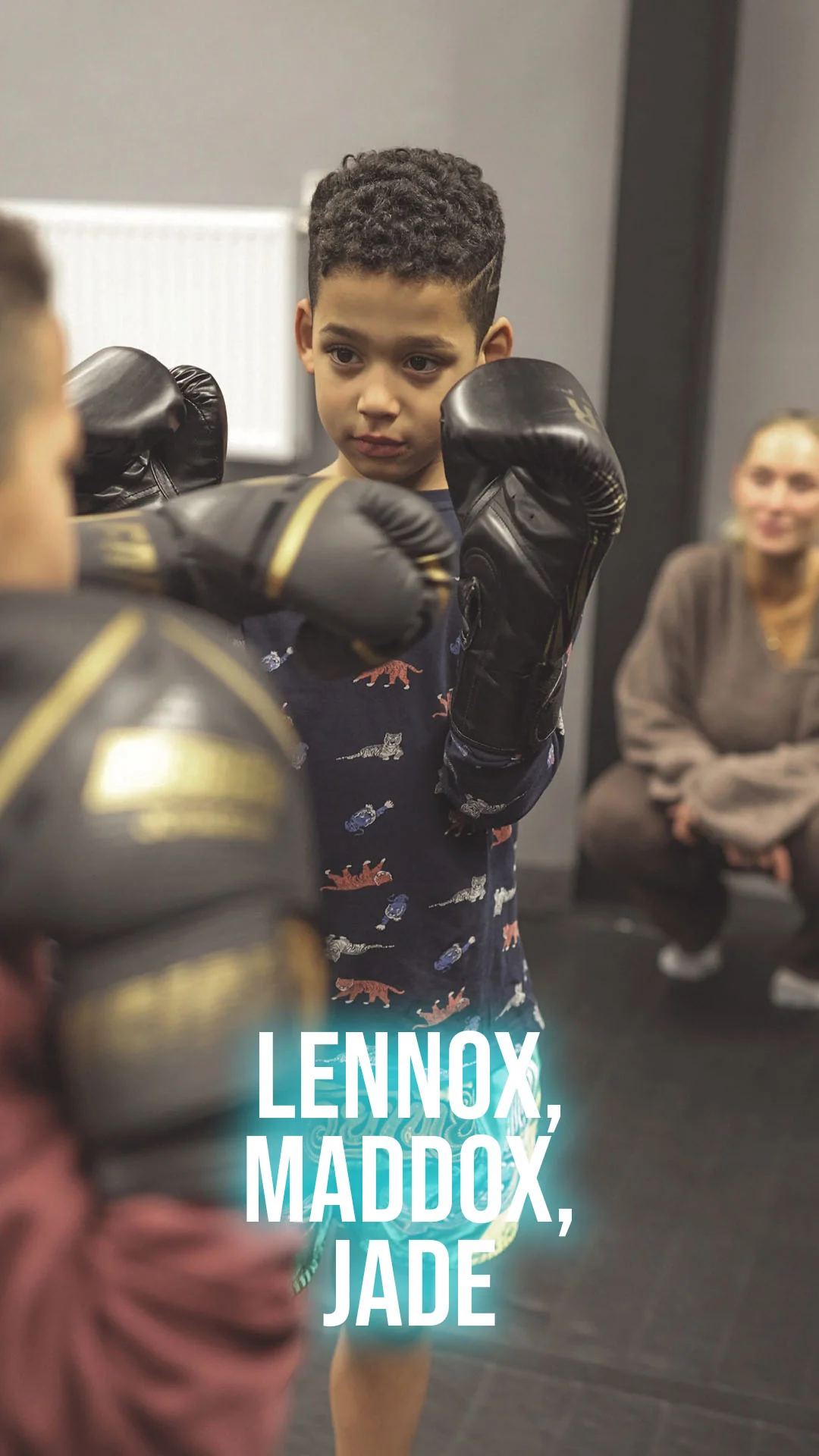 Lennox mit Boxhandschuhen beim Kindertraining, daneben Jade und Maddox