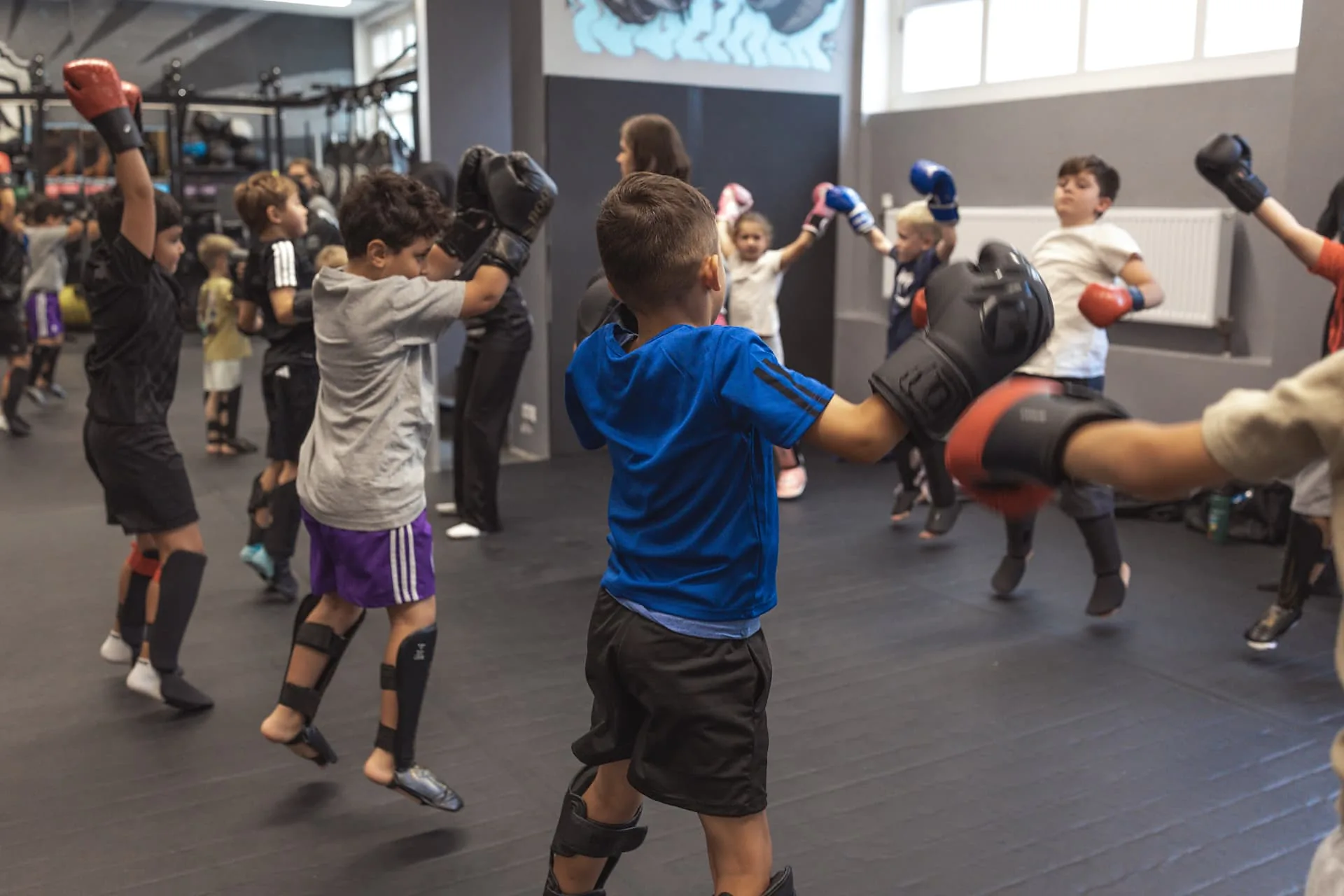 Kindergruppe schlägt und kickt gemeinsam beim Warm-Up in die Luft