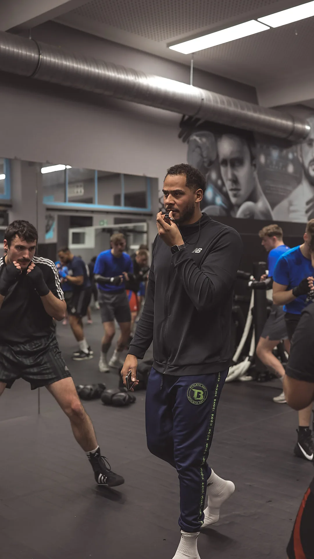 Trainer Philipp pfeift die nächste Runde an, im Hintergrund trainiert die Boxgruppe in der Halle der Barmbek Basch Fightschool