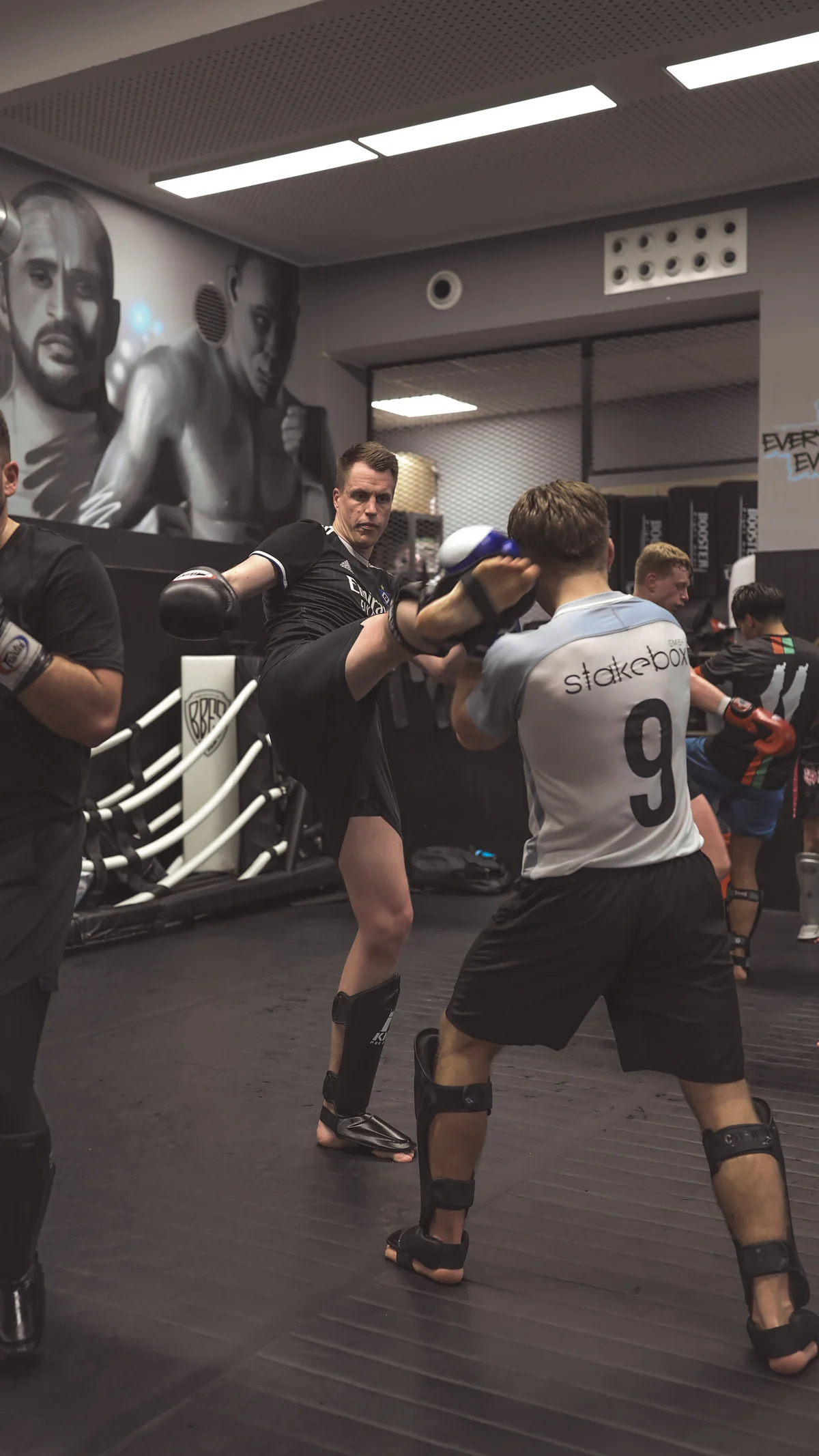 Kickboxer setzt im Training einen High Kick gegen die Pratze seines Partners