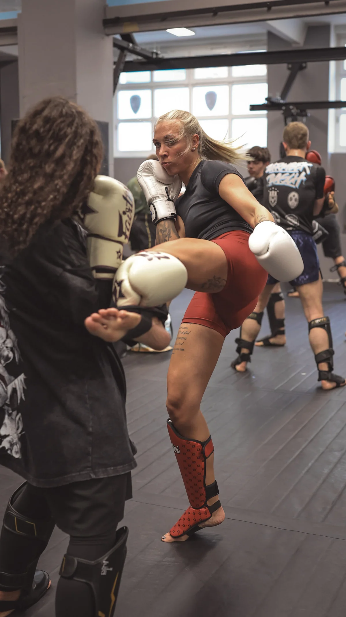 Kickboxerin trifft im Sparring mit einem hohen Kick — Training in der Barmbek Basch Fightschool